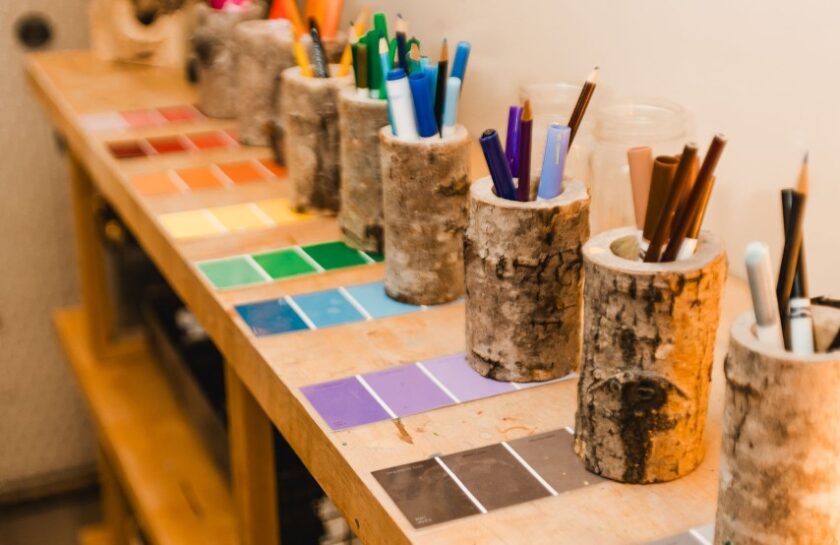 Different colored pencils and markers in cup holders made from tree bark.