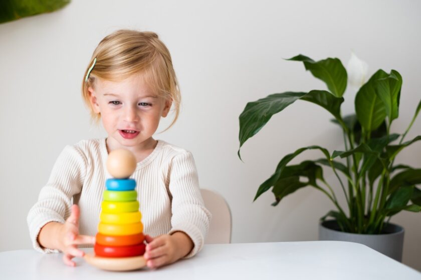 A little girl playing with a rainbow stacker.